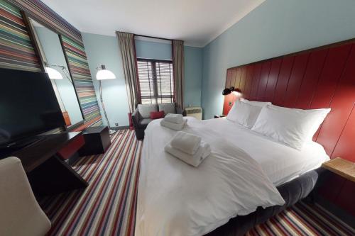 a hotel room with a large bed and a flat screen tv at Village Hotel Swindon in Swindon
