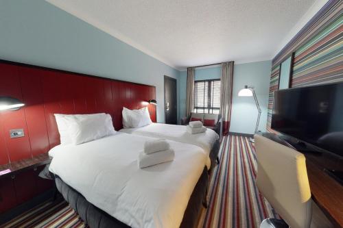 a hotel room with a large bed and a flat screen tv at Village Hotel Swindon in Swindon