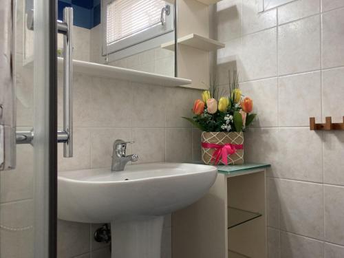 een badkamer met een wastafel en een vaas met bloemen bij Romea in Rosolina Mare