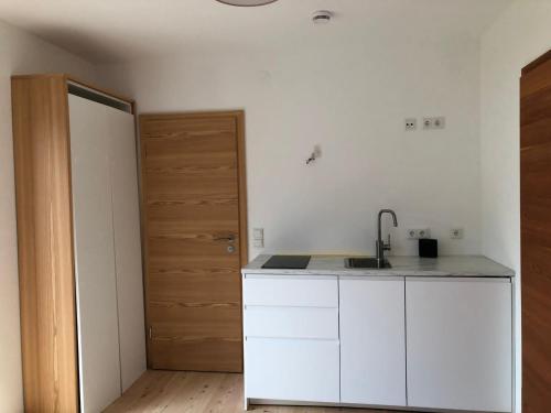 a white kitchen with a sink and a door at Seehof Apartments in Walchensee
