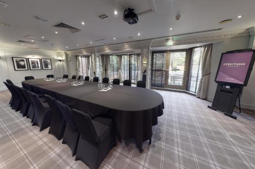 a conference room with a long table and chairs and a projection screen at Village Hotel Swindon in Swindon