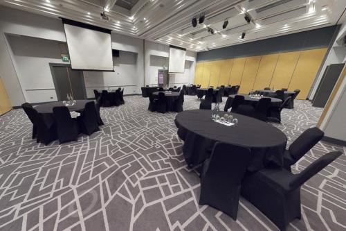 a conference room with tables and chairs and a screen at Village Hotel Swindon in Swindon