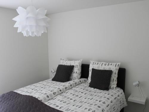 Bett mit schwarzweißer Bettwäsche und Kissen in der Unterkunft Bungalow near Veerse Meer with Private Garden in Kamperland