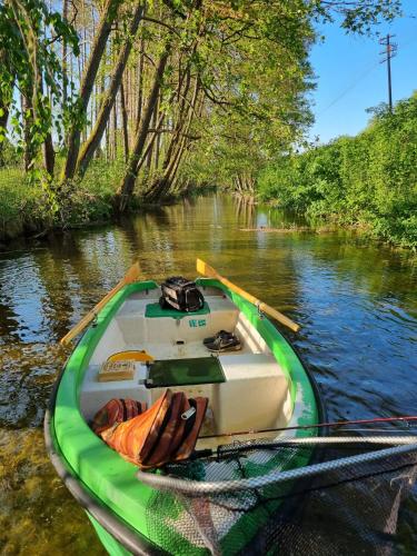 a green and white boat parked on a river at Przystań Piława in Borne Sulinowo