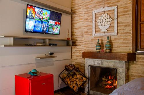 a living room with a fireplace and a flat screen tv at Recanto Meu Pedacinho de Chão in Visconde De Maua