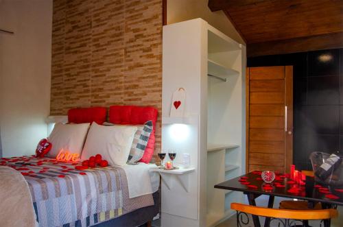 a bedroom with a bed with red pillows and a table at Recanto Meu Pedacinho de Chão in Visconde De Maua