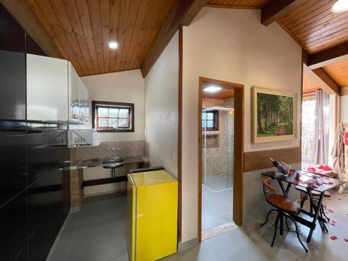 a kitchen with a yellow trash can and a table at Recanto Meu Pedacinho de Chão in Visconde De Maua