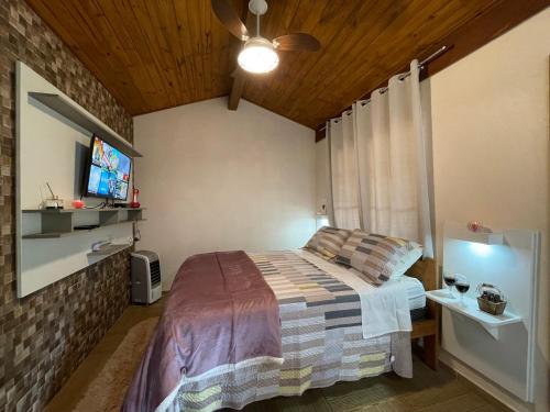 a bedroom with a bed and a flat screen tv at Recanto Meu Pedacinho de Chão in Visconde De Maua