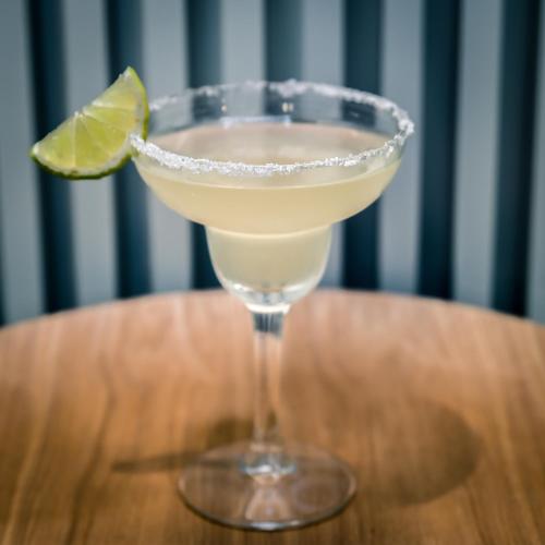 a martini glass with a lime on a wooden table at Aparthotel Mariano Cubi Barcelona in Barcelona