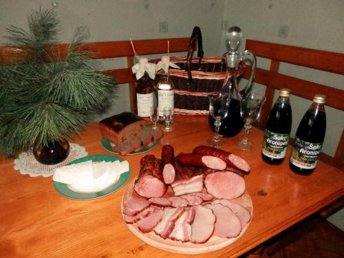 a table with a plate of meat and bottles of wine at Biebrza24 - Agroturystyka in Sztabin