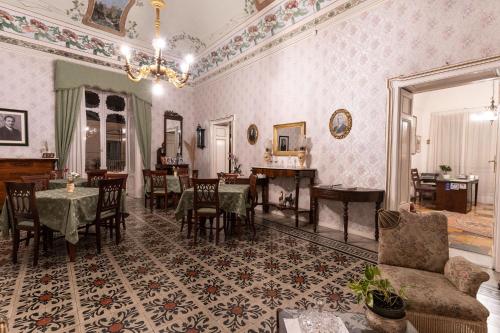 a dining room with tables and chairs and a chandelier at Palazzo Il Cavaliere B&B De Charme in Modica