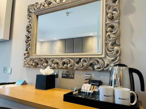 a mirror on a wall above a table with mugs at Boston West Hotel in Boston