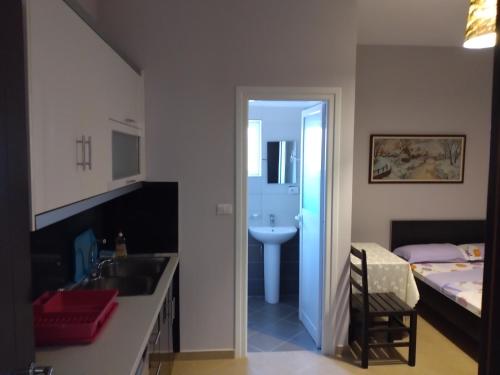 a bathroom with a sink and a bedroom with a bed at Xuxi Apartments in Lukovë