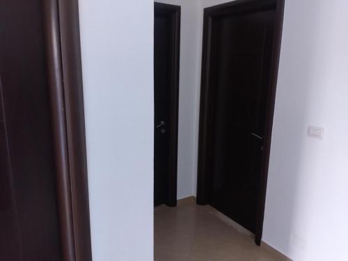 a hallway with two black doors and a white wall at Xuxi Apartments in Lukovë