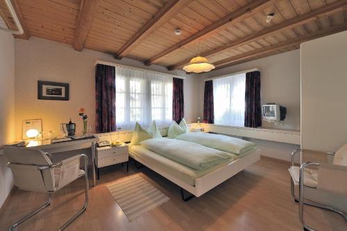 a bedroom with a bed and a desk and windows at Seminarhotel Linde Stettlen in Bern