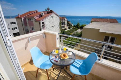 einen Balkon mit einem Tisch, Stühlen und Meerblick in der Unterkunft Apartmani Dubrava in Podstrana