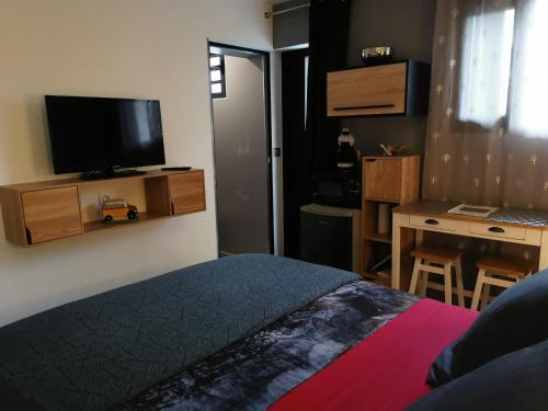 a bedroom with a bed and a desk and a television at Hostal 170 Room 15 Service Appartement in Le Tampon