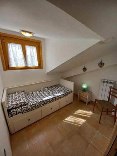 羅卡拉索的住宿－Roccaraso Inn Blu，一间卧室设有一张床、一个窗口和一把椅子