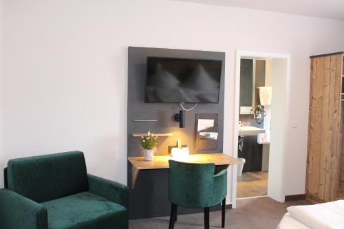 Habitación con escritorio, silla y espejo. en Hotel Häußler en Langenbruck