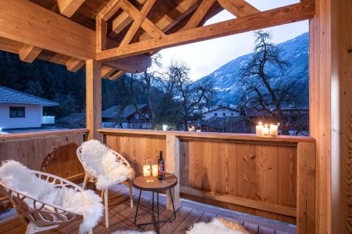 un porche cubierto con 2 sillas y una mesa en Griena NaturChalets ****, en Mayrhofen