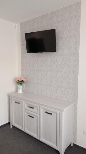 a white cabinet with a television on a wall at Penzion HARMONIE in Trhové Sviny