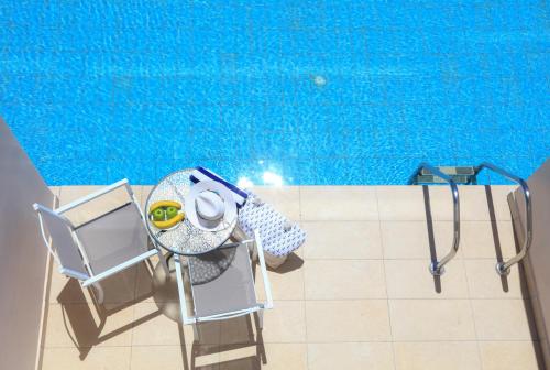 a pool with two chairs and a table and a swimming pool at Cavomarina Beach- Adults Only in Kavos