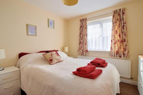 una camera da letto con un letto con asciugamani rossi di Bridge House Apartment a Charmouth