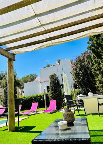 a patio with pink chairs and a table in a yard at Can Mossènyer in San Antonio