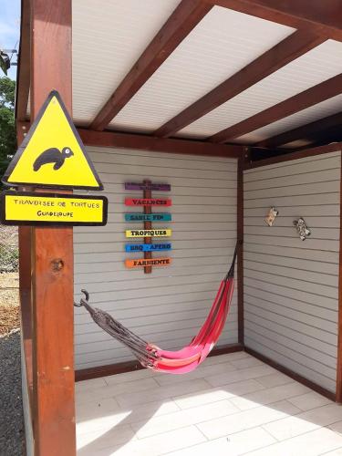 a hammock in front of a garage with a sign at Archipel Maimeo in Saint-François