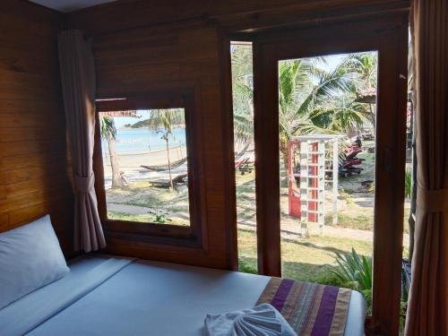 a bedroom with a bed and a view of the beach at Tommy Resort in Haad Rin