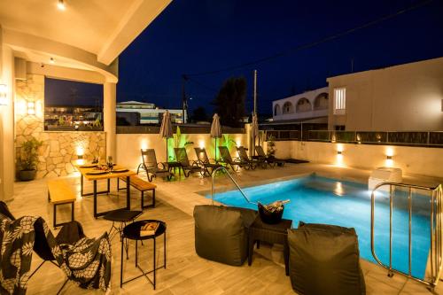 a swimming pool with tables and chairs on a patio at Old Cinema Suites - Stylishly Decorated Retreat with Pool or Jacuzzi by the Sea in the Heart of Laganas Βy Villa Mana Gers in Laganas