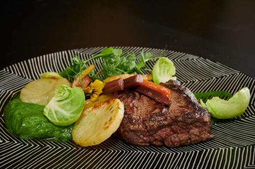 a plate of food with a piece of meat and vegetables at Hôtel du Beffroi Gravelines Dunkerque in Gravelines