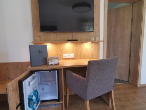 a desk with a chair and a television on a wall at Hotel Grüner Baum mit Restaurant & Wellness in Beerfelden