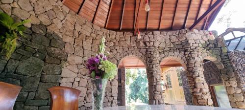 a vase of flowers on a table in a stone wall at Avalon Ubud Castle & SPA in Ubud