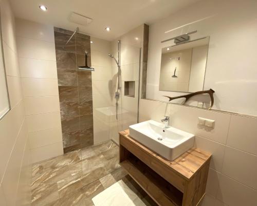 y baño blanco con lavabo y ducha. en Appartements Zwölferkogelblick, en Saalbach Hinterglemm