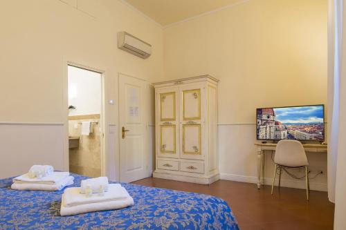 a room with two beds and a desk and a television at Relais Tiffany in Florence