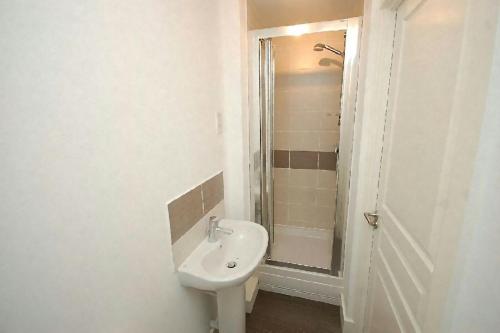y baño blanco con lavabo y ducha. en Park House B&B en Leeds