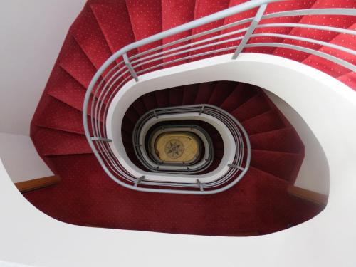 a spiral stair case with red carpet and a goldrine at Alle Porte in Riva del Garda