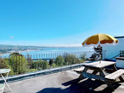 a wooden picnic table with an umbrella on a balcony at Shan Mu Inn Entire flat 2 bedrooms with terrace seaview BBQ in Newlyn