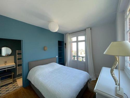 une chambre bleue avec un lit et une table avec une lampe dans l'établissement Chantemerle à partir de 2 personnes, à Villers-sur-Mer