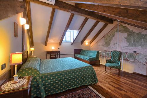 a bedroom with a bed and chairs in a attic at Palazzo Vescovile Hotel in Noli