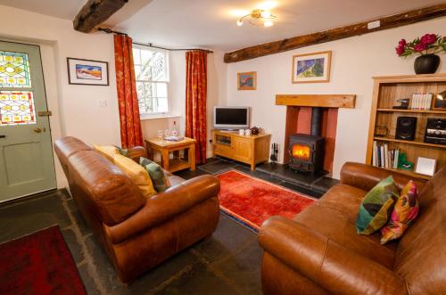 a living room with two leather couches and a fireplace at Peggy Hill Cottage in Ambleside