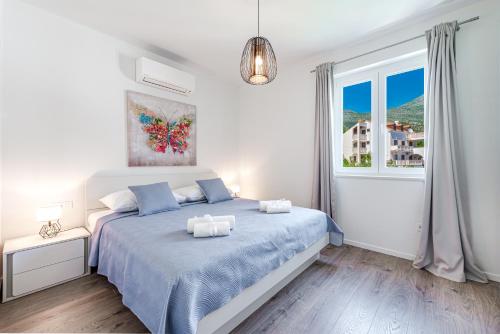 a white bedroom with a blue bed and a window at Amazing Sea View Apartments Petra & Paula in Slano