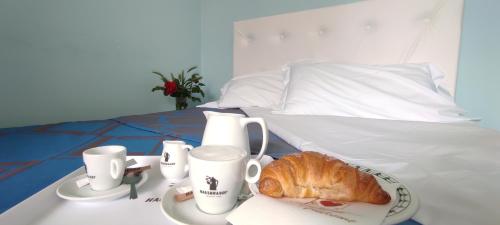 a table with a plate of bread and cups on a bed at Villa Mirella-NUOVA GESTIONE in Grado