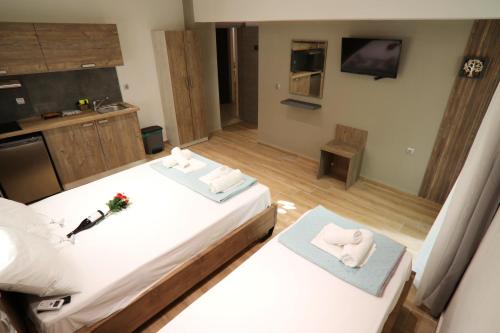 a bedroom with two beds and a kitchen with a tv at LDG Rooms in Olympiaki Akti