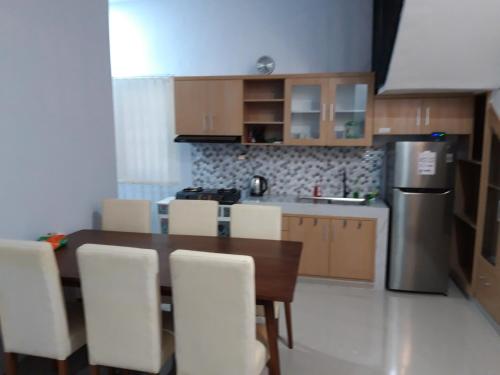 a kitchen with a wooden table and white chairs at Huize Silitonga in Malang