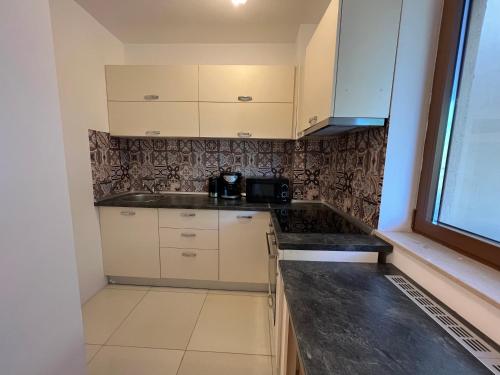 布拉索夫Coroni studio with jacuzzi的厨房配有白色橱柜和黑色台面