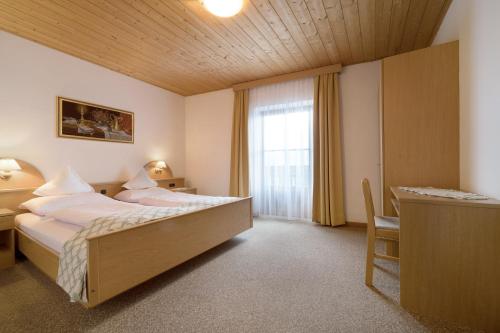 a bedroom with a bed and a desk and a window at Apartment Dolomitenblick in Mühlbach