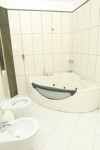 a bathroom with a tub and a toilet and a sink at Hotel Autostrada (Highway) in Kashari