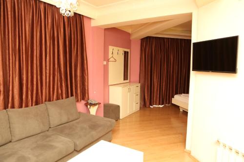 a living room with a couch and a flat screen tv at Hotel Autostrada (Highway) in Kashari
